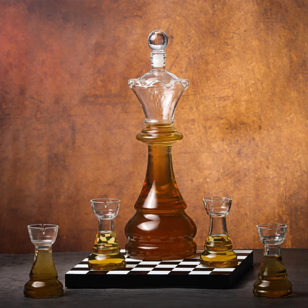 A crystal glass whiskey decanter shaped like a chess king piece, filled with amber liquor, surrounded by four matching shot glasses shaped like chess rook pieces, resting on a small black and white chessboard tray.