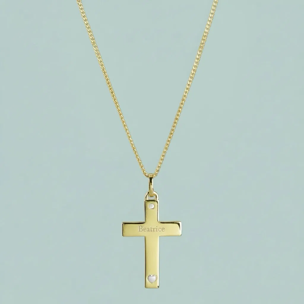 A personalised 9ct gold cross necklace featuring a delicately engraved name 'Beatrice' and a small heart detail near the base. The cross is suspended from a double layered gold chain and also features a small two heart-shaped embedded crystal accents. The necklace is photographed against a smooth, duck egg blue background, highlighting the quality of the gold and the personalisation. Ideal gift for a christening, confirmation, or anniversary.