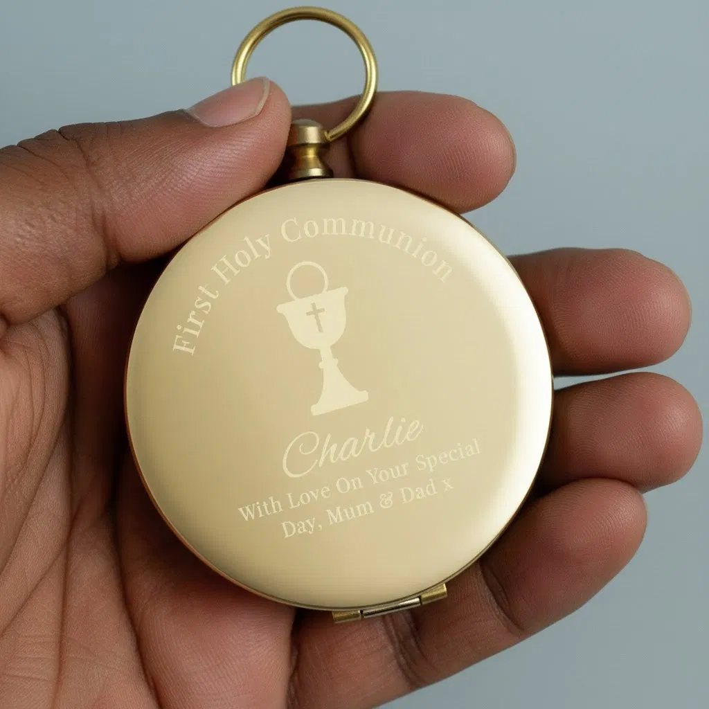 gold-toned personalised compass held in a hand, engraved with 'First Holy Communion' text, a Chalice symbol, the name 'Charlie,' and a loving message 'With Love On Your Special Day, Mum & Dad x'. Ideal sentimental gift for a First Holy Communion.