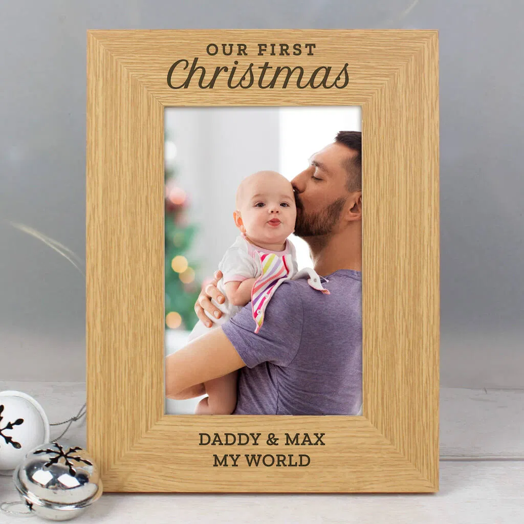 Personalised 'Our First Christmas' Photo Frame in wood, featuring fixed text and custom names engraved below the space for a 6x4 photo.