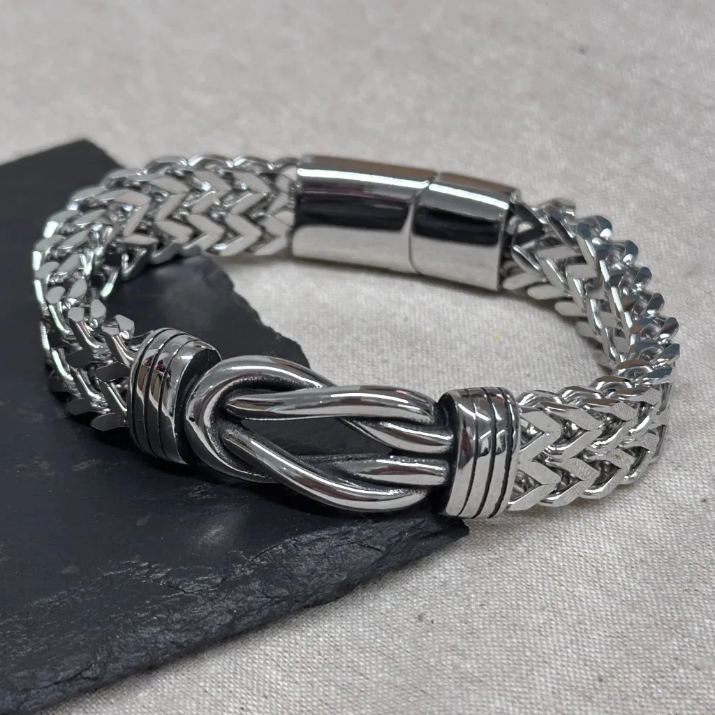 Personalised men's woven leather bracelet featuring an engraved infinity knot symbol and magnetic clasp, worn on a male wrist.