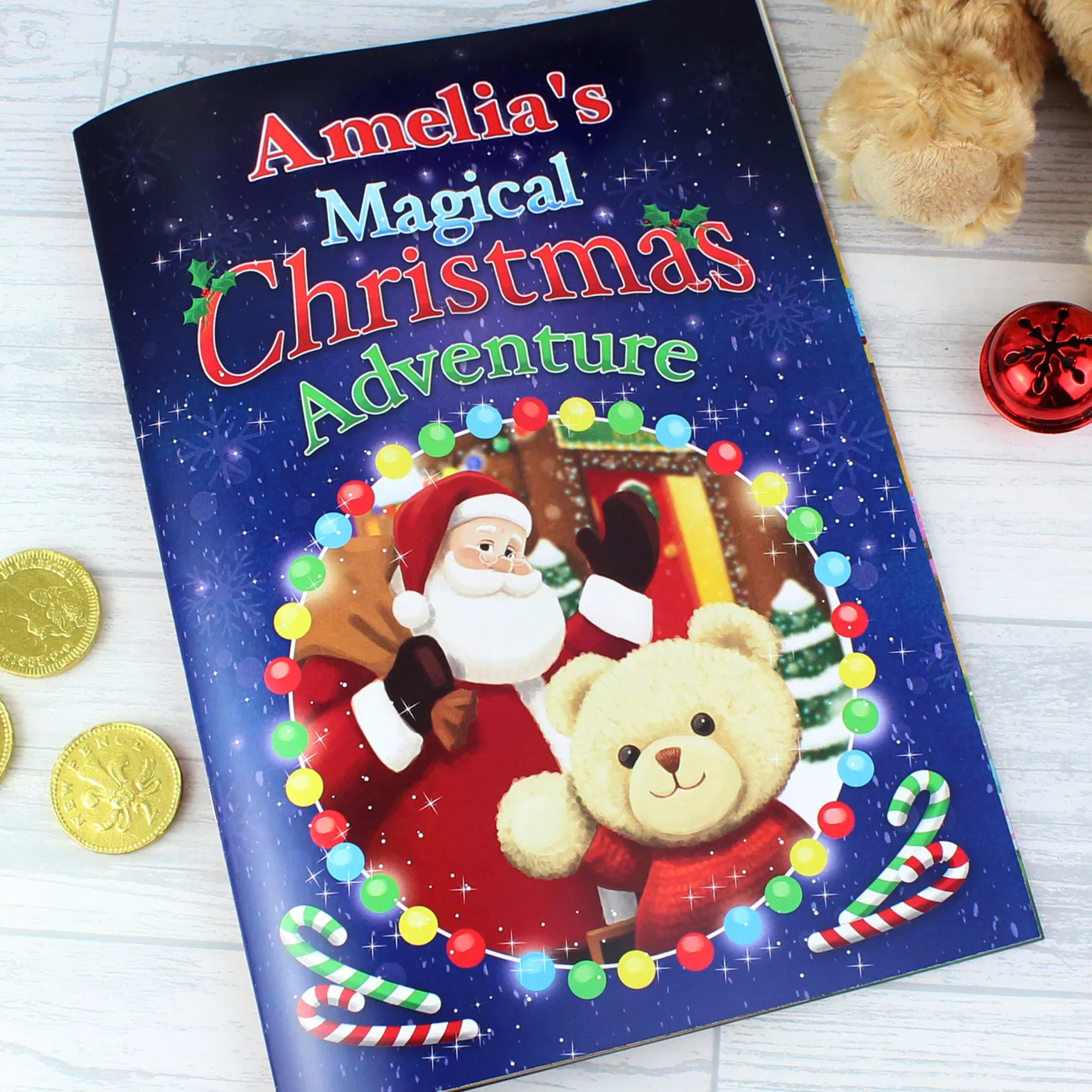 P0512Z41.jpg (Front Cover - Amelia): Close-up of the front cover of 'Amelia's Magical Christmas Adventure Story Book.' It shows Santa Claus and a teddy bear surrounded by festive lights against a dark blue background.