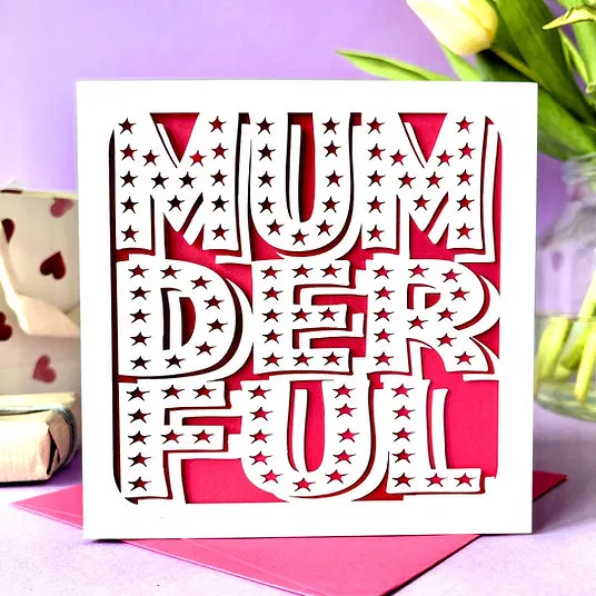 Alt Text: A luxury square Mother's Day card featuring the word "MUMDERFUL" in a bold, white laser-cut font with intricate star-shaped cut-outs, layered over a vibrant pink background with a matching pink envelope.