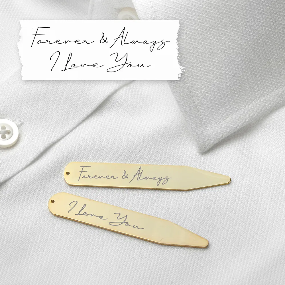 A pair of luxurious 18K gold-plated collar stiffeners resting on a crisp white dress shirt. The stiffeners are engraved with genuine handwriting; the top one reads "Forever & Always" and the bottom one reads "I Love You." Above the shirt, a white paper strip shows the original handwritten note.