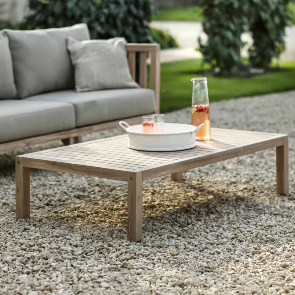 Rectangular whitewash acacia wood coffee table styled with summer drinks on a gravel patio.