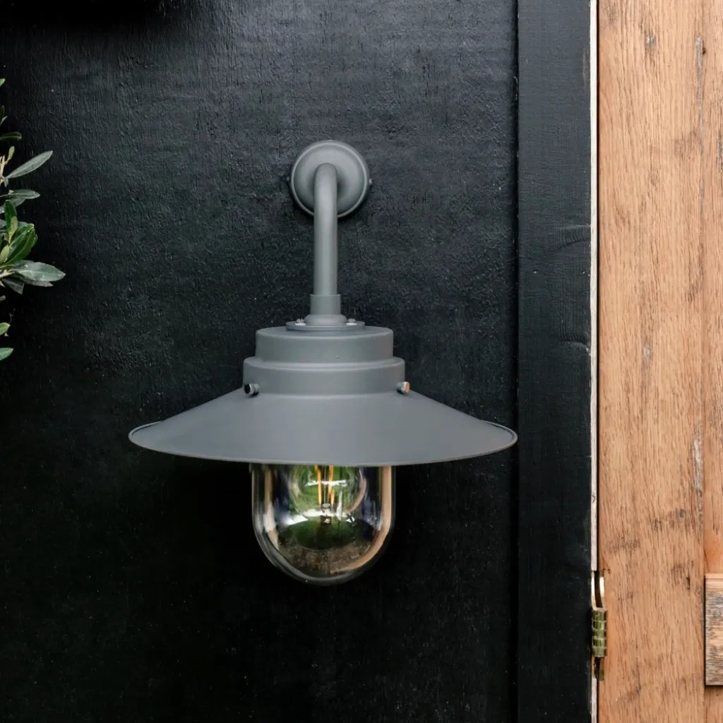 HMS Belfast inspired Charcoal deck light mounted on a black wooden wall next to a timber door.
