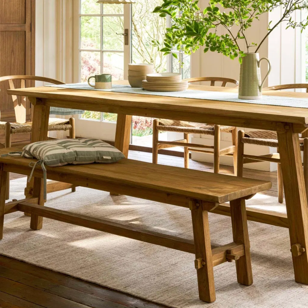 Reclaimed teak dining bench paired with a matching trestle dining table.