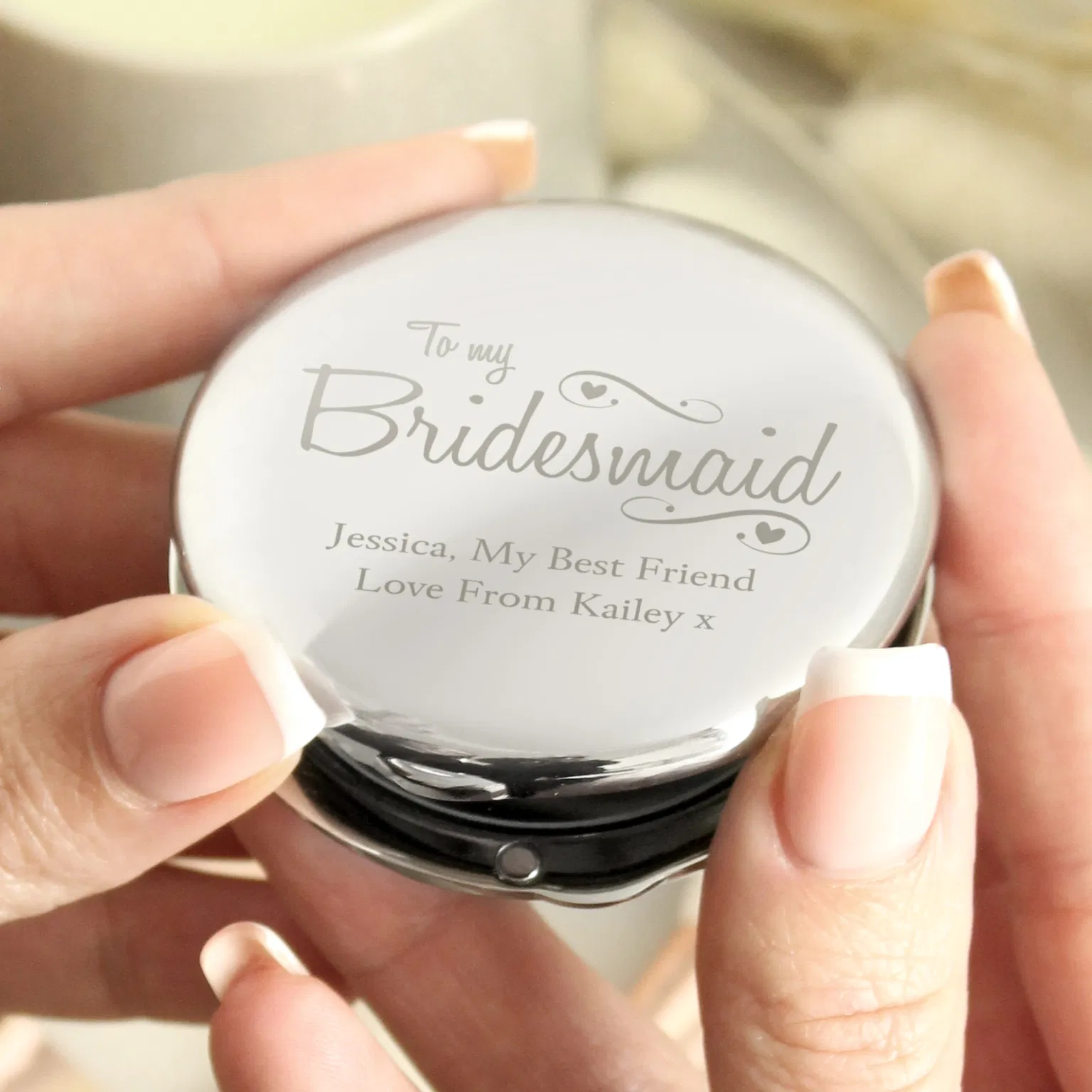 Polished nickel-plated compact mirror engraved with To my Bridesmaid and a custom message placeholder next to its black fabric pouch.