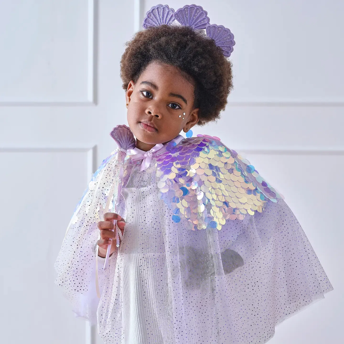 Young girl with an afro wearing a luxury purple mermaid princess costume cape with iridescent scales, matching wand, and seashell crown headband.
