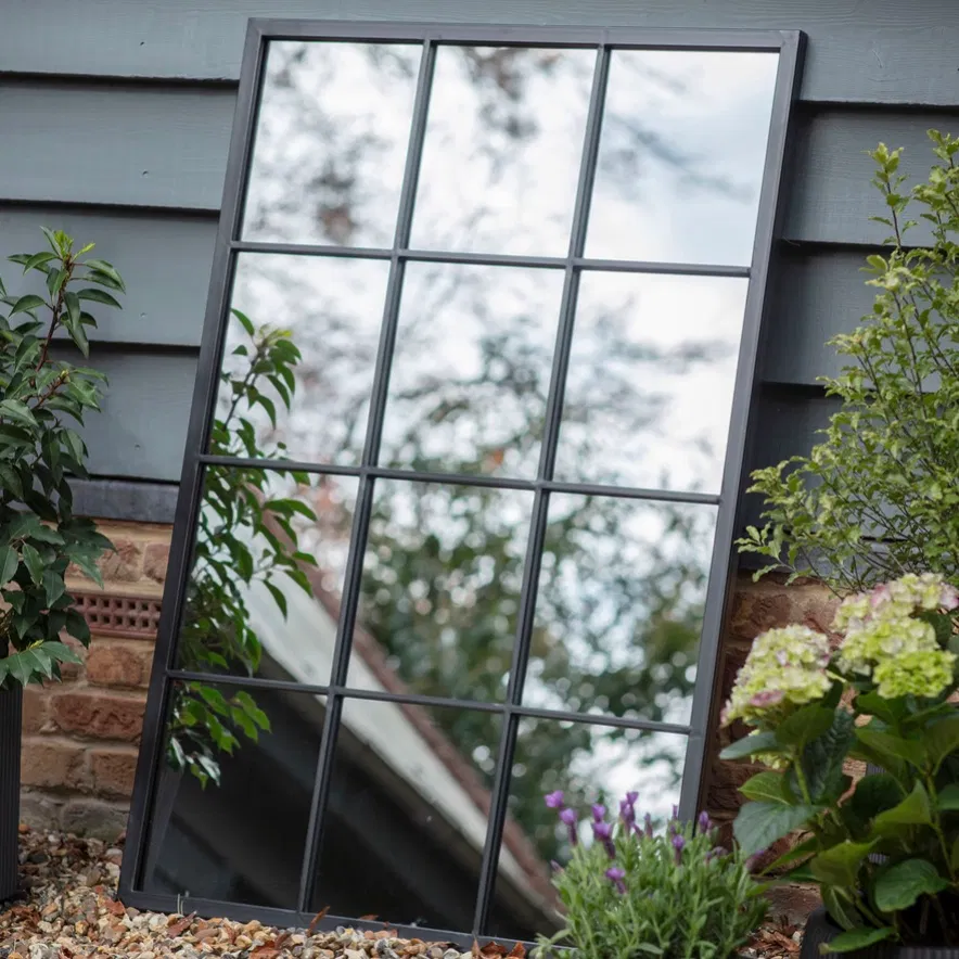 The 120x80cm large rectangular black metal window pane mirror mounted landscape on a brick garden wall by Abode Home & Gifts.