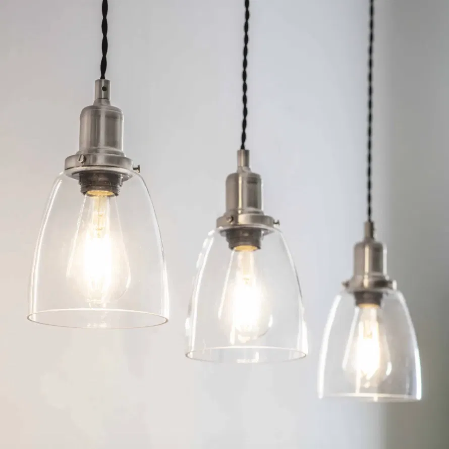Three linear glass dome pendant lights with satin nickel fittings glowing against a neutral background by Abode Home & Gifts.