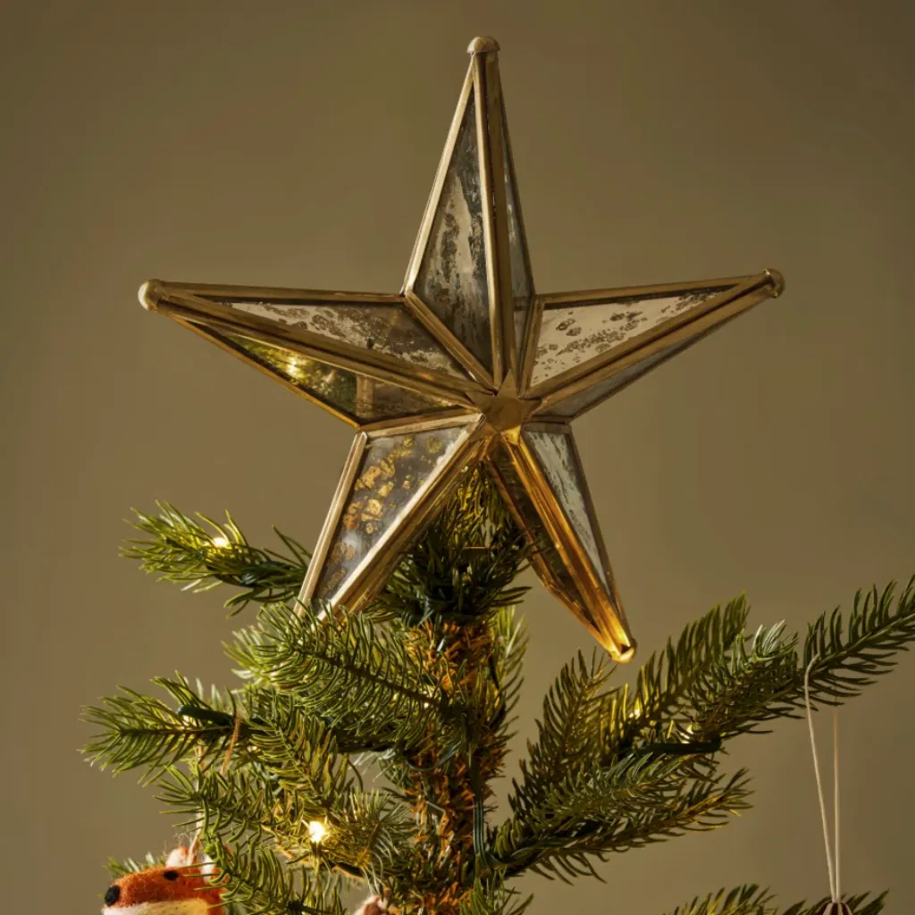 Windermere antique brass and mirrored glass star tree topper by Abode Home & Gifts sitting securely on a lit Christmas tree.